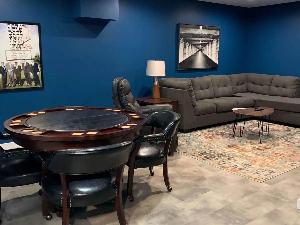 A social corner featuring a poker table ready for games, paired with a comfortable sofa and vibrant artwork on the walls. The setup is perfect for board games, cards, or casual gatherings, encouraging connection and shared experiences.